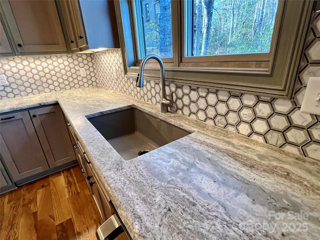 kitchen featuring light stone counters, dark hardwood / wood-style flooring, sink, and decorative backsplash