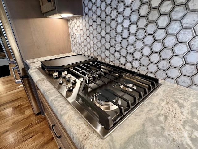 details with tasteful backsplash, stainless steel gas cooktop, and dark hardwood / wood-style floors