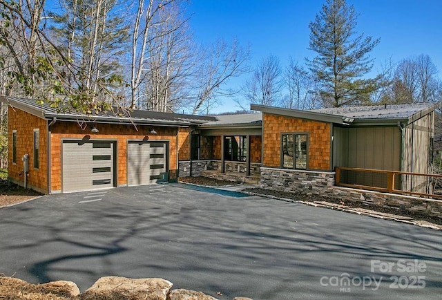 view of front facade with a garage, stone siding, and driveway