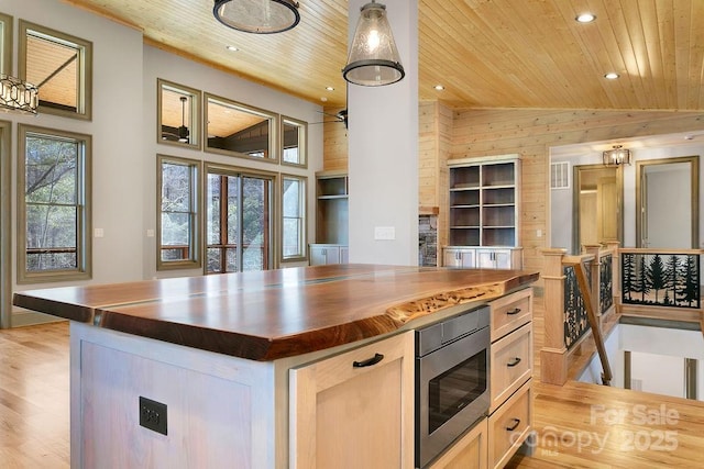 kitchen with butcher block countertops, stainless steel microwave, wooden ceiling, and a center island