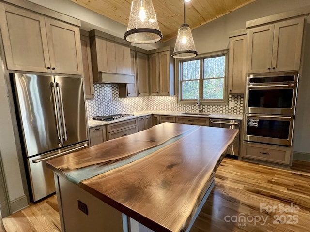 kitchen with wooden ceiling, appliances with stainless steel finishes, decorative light fixtures, light wood-type flooring, and backsplash