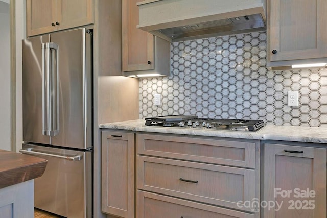 kitchen featuring wall chimney exhaust hood, appliances with stainless steel finishes, light countertops, and backsplash