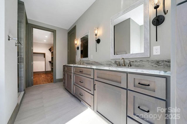 bathroom featuring a sink, a spacious closet, and double vanity