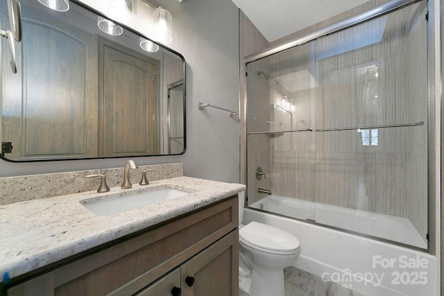 bathroom with enclosed tub / shower combo, vanity, and toilet