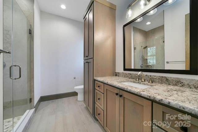 bathroom featuring baseboards, toilet, wood finished floors, vanity, and a shower stall