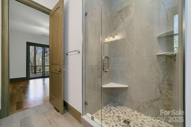 bathroom featuring baseboards, a marble finish shower, and wood finished floors