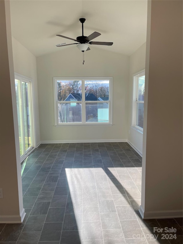 unfurnished room featuring ceiling fan, dark tile patterned floors, and lofted ceiling