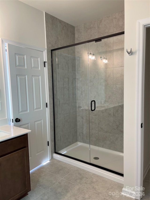 bathroom with tile patterned flooring, vanity, and an enclosed shower