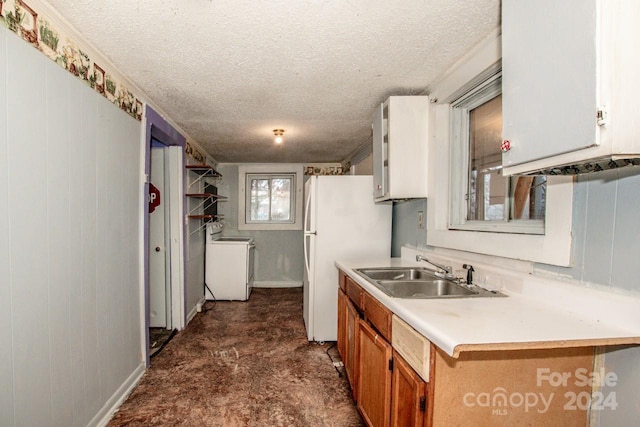 kitchen featuring washer / clothes dryer, sink, a textured ceiling, and white refrigerator