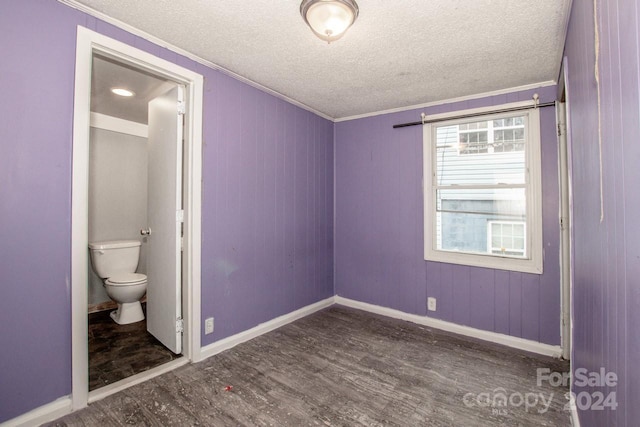 unfurnished bedroom with connected bathroom, dark hardwood / wood-style floors, and ornamental molding