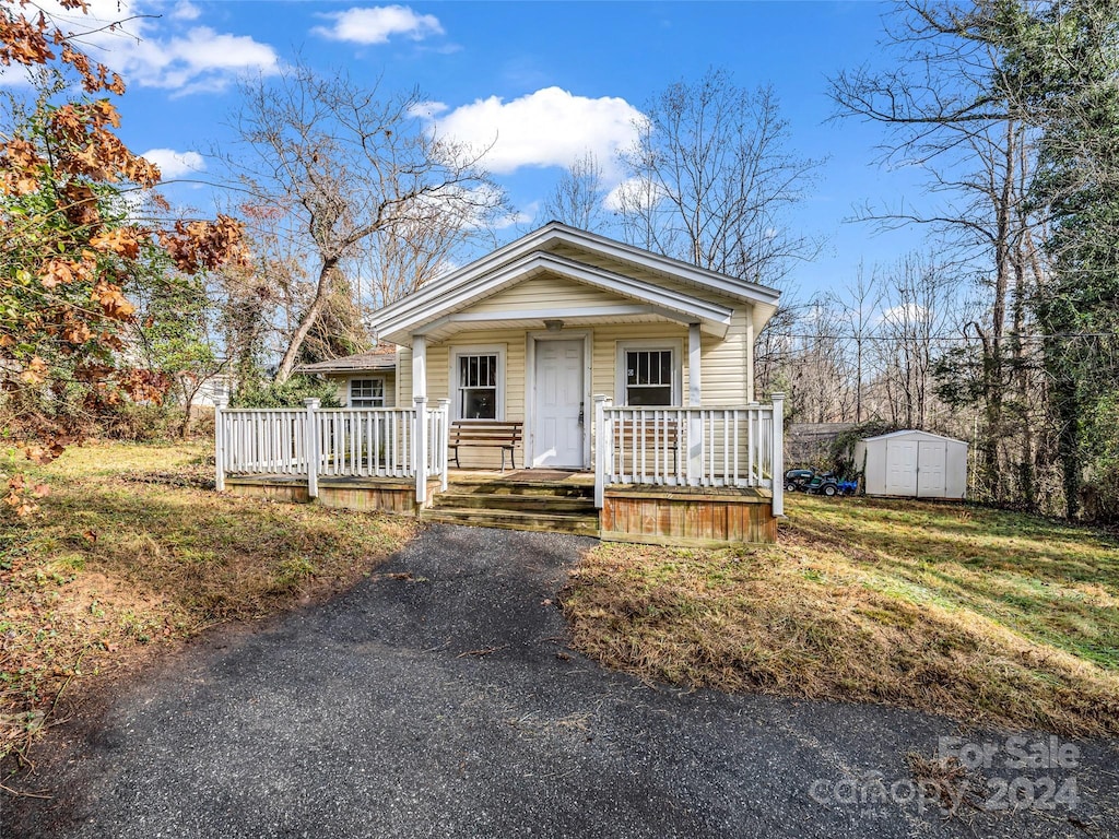 bungalow-style house with a porch and a storage shed