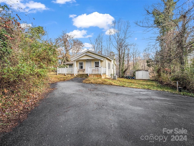 view of front of property with a front yard, a porch, and a shed