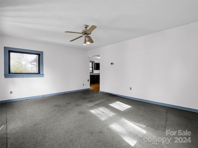 empty room featuring dark colored carpet, a textured ceiling, and ceiling fan