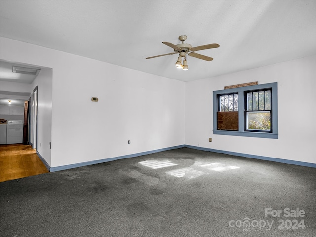 empty room with dark colored carpet, ceiling fan, and independent washer and dryer