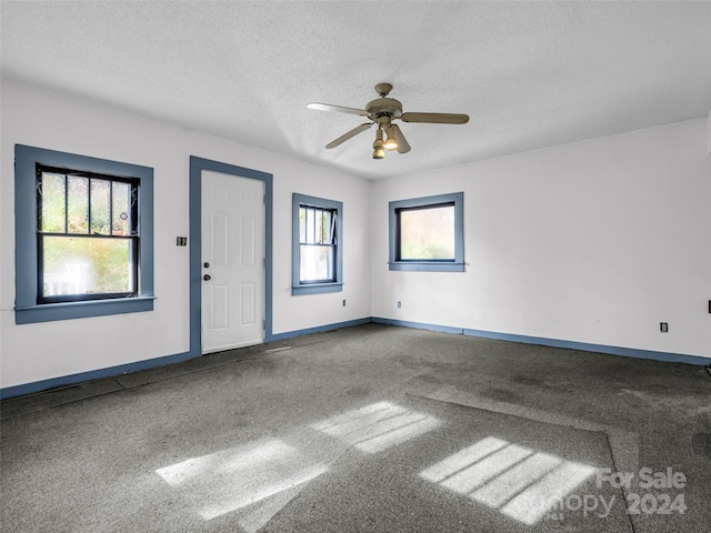 carpeted spare room featuring a textured ceiling and ceiling fan