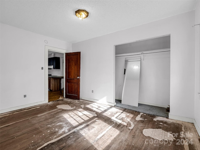 unfurnished bedroom featuring dark hardwood / wood-style flooring, a textured ceiling, and a closet