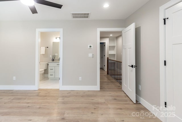 unfurnished bedroom with light wood-type flooring, baseboards, visible vents, and ensuite bathroom