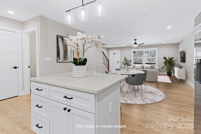 kitchen featuring white cabinets, light wood-style floors, a center island, a ceiling fan, and recessed lighting