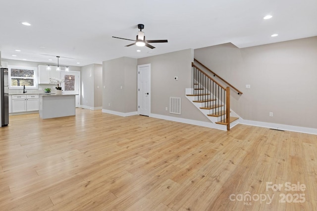 unfurnished living room with stairway, recessed lighting, ceiling fan, and light wood finished floors
