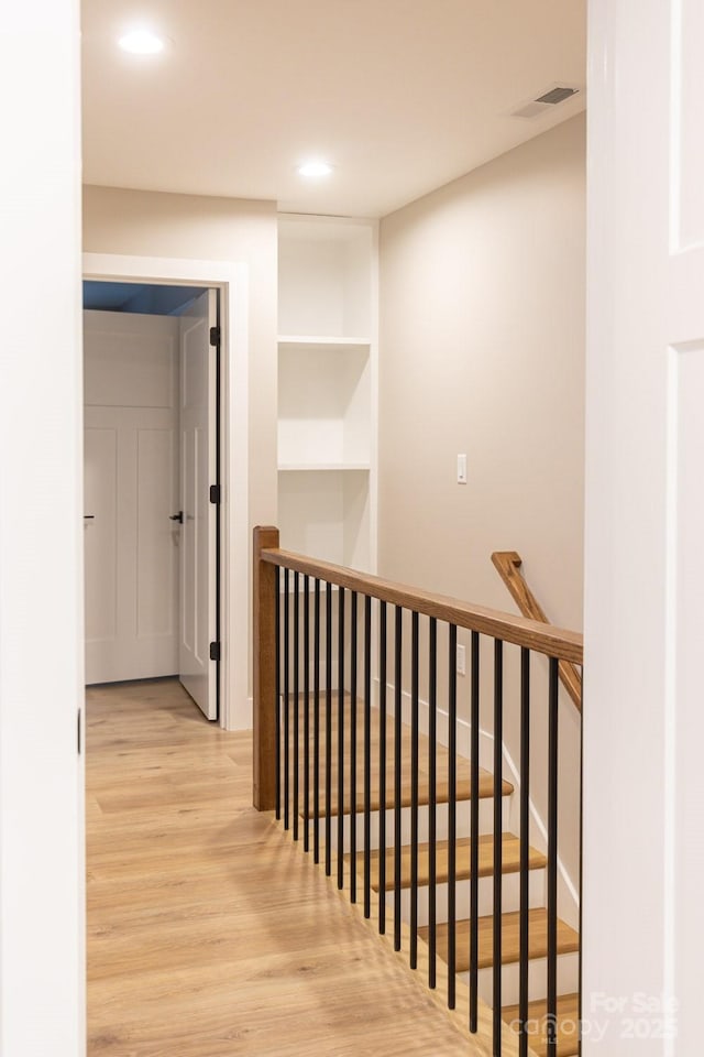hall with visible vents, recessed lighting, wood finished floors, and an upstairs landing