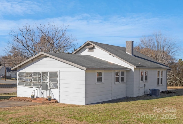 view of side of property with central AC and a lawn