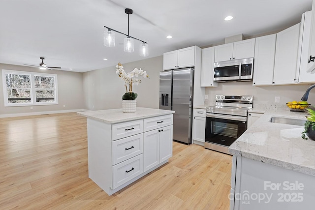 kitchen featuring recessed lighting, stainless steel appliances, a sink, white cabinets, and light wood-style floors