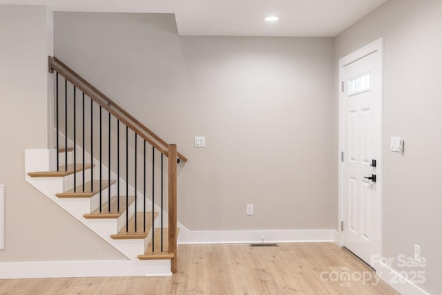 foyer featuring visible vents, baseboards, and wood finished floors