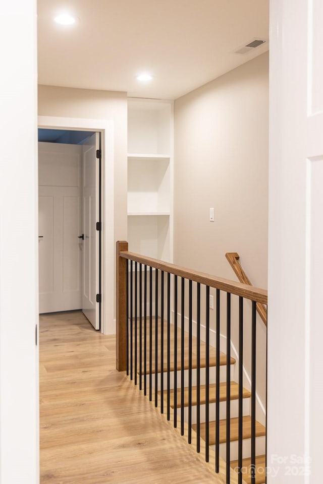 hallway with wood finished floors, visible vents, and recessed lighting