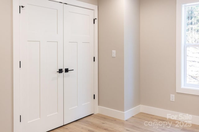 unfurnished bedroom with light wood-style floors, a closet, and baseboards