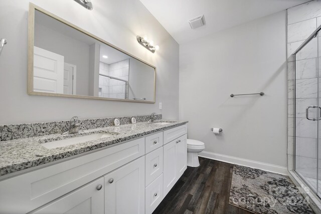 bathroom with toilet, vanity, a shower with shower door, and hardwood / wood-style flooring