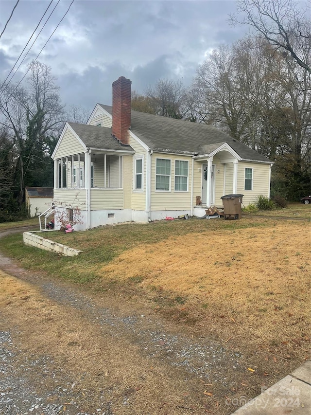 view of front of home with a sunroom, a front lawn, and a hot tub