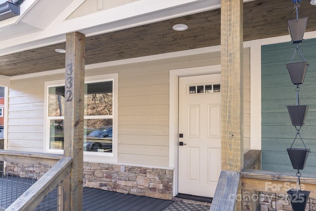 view of exterior entry with stone siding and a porch