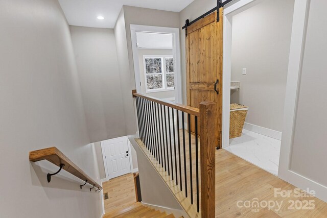 stairway featuring recessed lighting, wood finished floors, baseboards, and a barn door