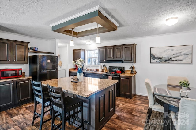 kitchen featuring black appliances, a kitchen island, dark hardwood / wood-style flooring, and dark brown cabinetry