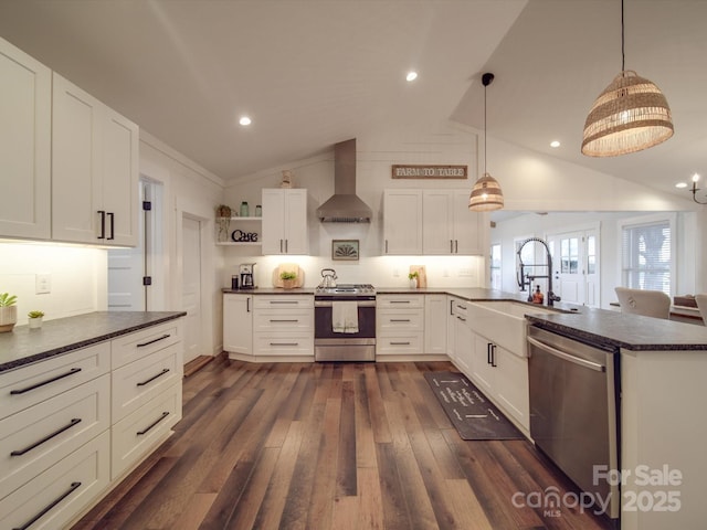 kitchen featuring pendant lighting, wall chimney range hood, appliances with stainless steel finishes, and vaulted ceiling