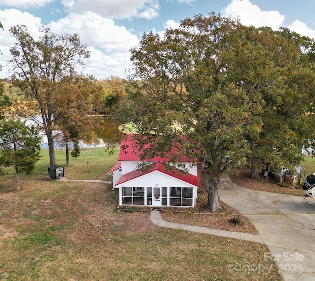 view of front of house with a sunroom, a water view, and a front yard