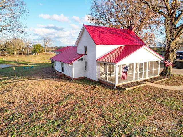 back of property featuring a lawn and a sunroom