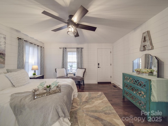 bedroom featuring ceiling fan, dark hardwood / wood-style flooring, and wooden walls