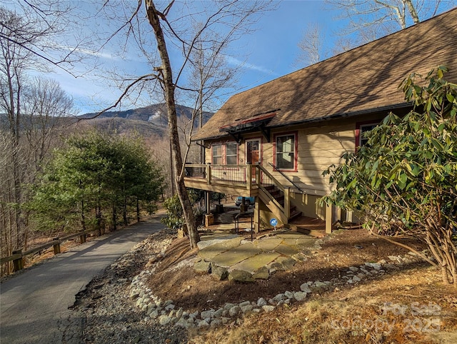 rear view of property with roof with shingles and a deck