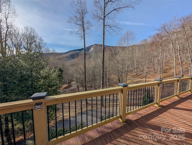 wooden terrace featuring a wooded view and a mountain view