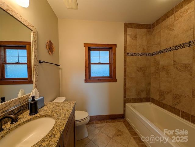 bathroom featuring a healthy amount of sunlight, vanity, toilet, and baseboards