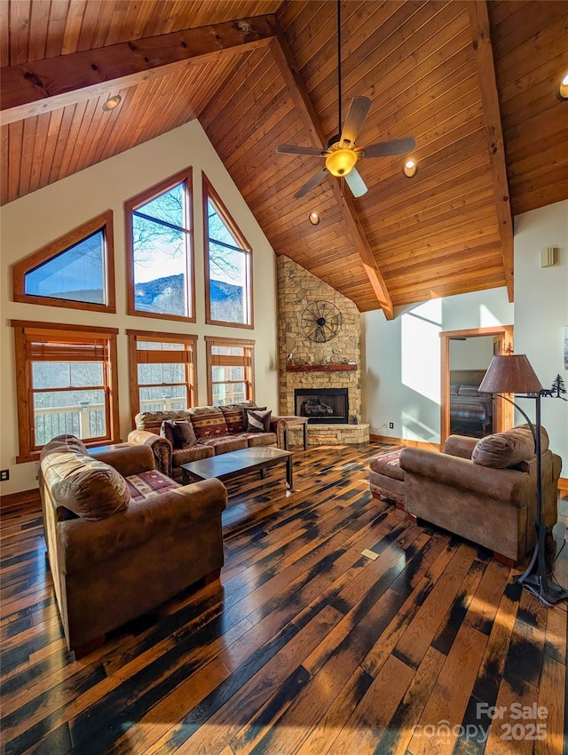 living area with hardwood / wood-style floors, a stone fireplace, beam ceiling, and a healthy amount of sunlight