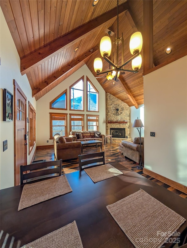 living area featuring high vaulted ceiling, wooden ceiling, a notable chandelier, a fireplace, and beam ceiling