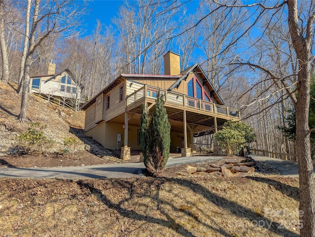 back of property featuring a deck, driveway, and a chimney