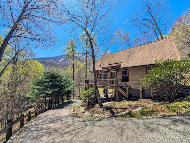 view of home's exterior featuring a shingled roof, a wooden deck, and stairs