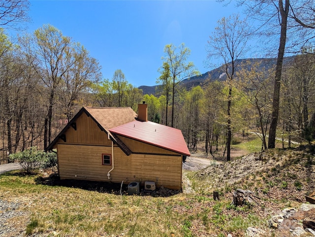view of side of property featuring a view of trees, a mountain view, and a chimney