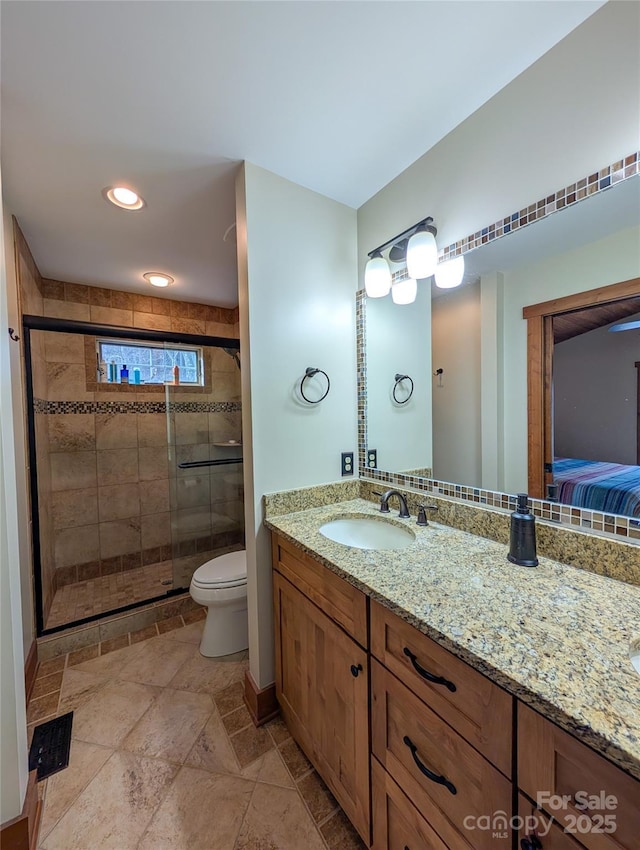 bathroom with vanity, stone tile floors, toilet, ensuite bathroom, and a shower stall