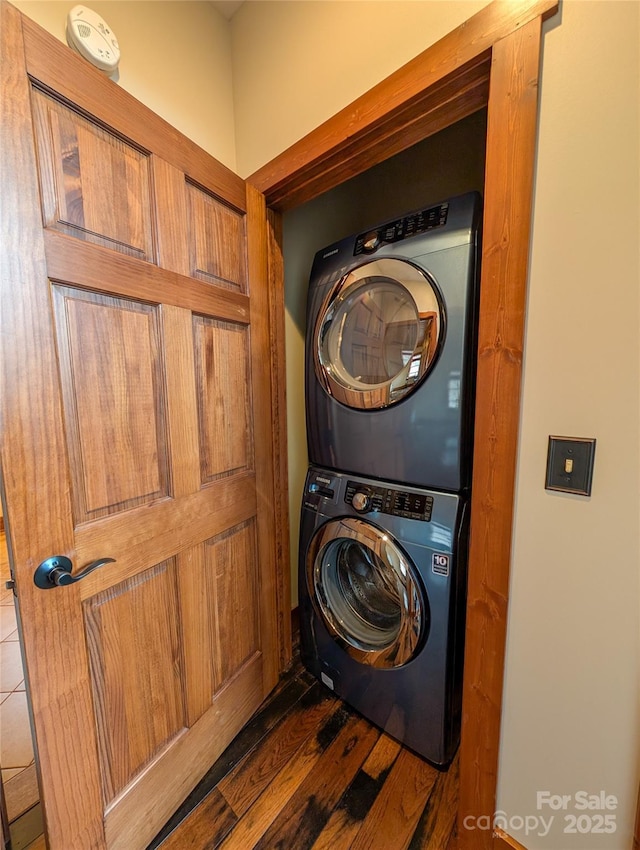 laundry room with dark wood finished floors, laundry area, and stacked washer and dryer