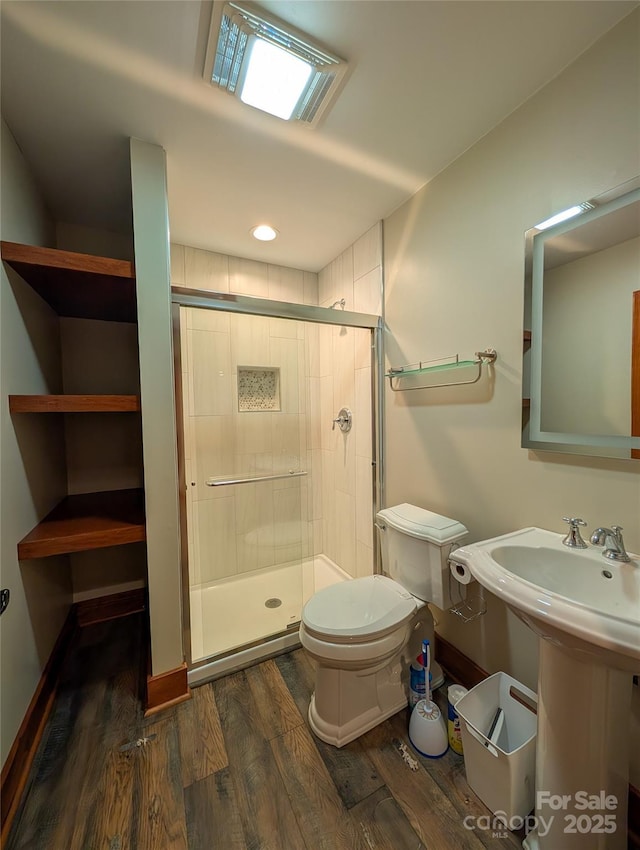 full bathroom featuring baseboards, wood finished floors, toilet, and a shower stall