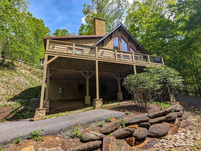 cabin with board and batten siding, a wooden deck, and a chimney